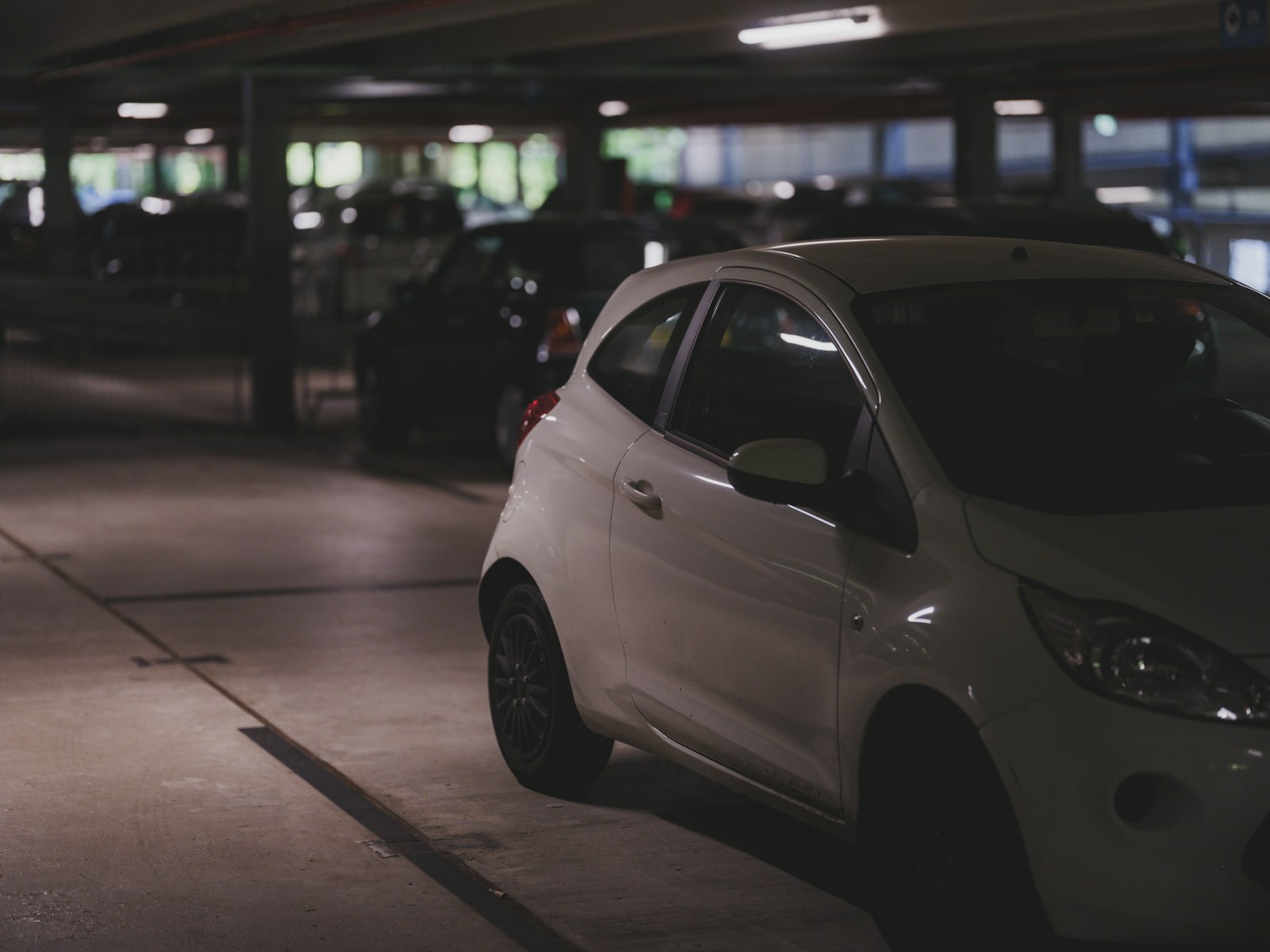 Cars are parked in a dimly lit parking garage.