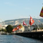A body of water with a bridge and a ferris wheel in the background
