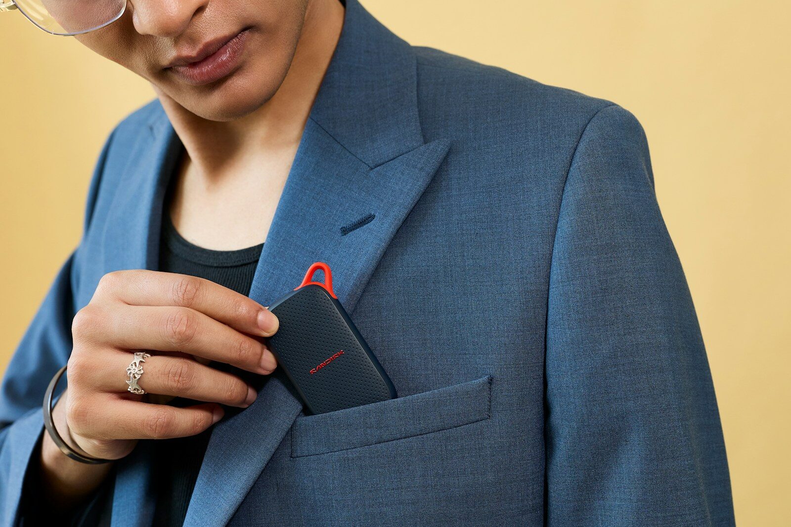 Hand inserting a black electronic device into a blazer pocket.